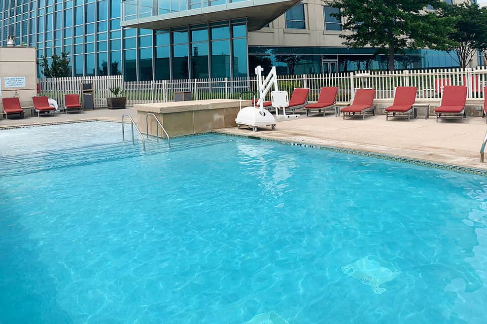 Resort outdoor pool with red lounge chairs and glass balcony railing