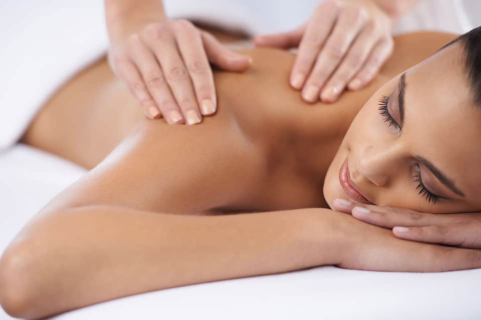 Woman receiving a relaxing back massage at a spa with hands applying pressure to shoulders