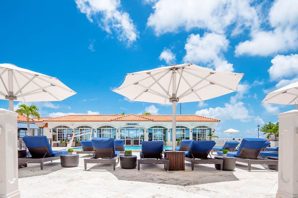 Beach club lounge area with white umbrellas, blue loungers, and ocean view