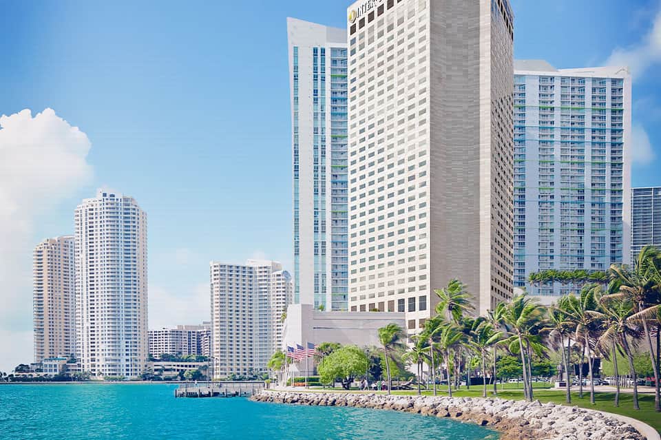 Beachfront high-rise hotel buildings along turquoise waterfront with palm trees and manicured lawns
