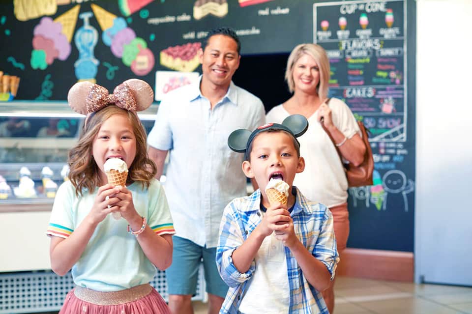 Family enjoying ice cream cones at a colorful ice cream parlor with playful decor