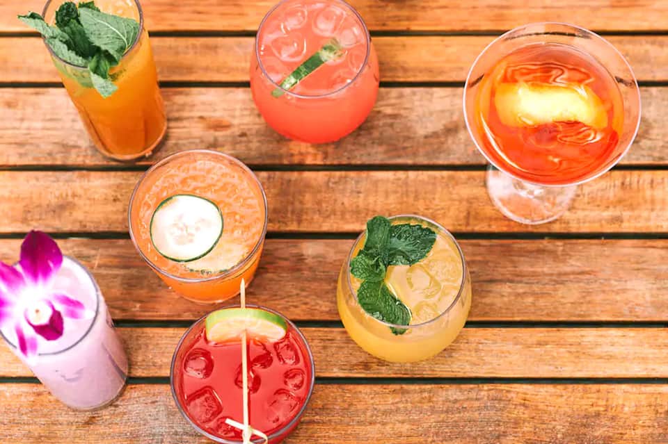 Overhead view of colorful tropical cocktails with garnishes on wooden deck