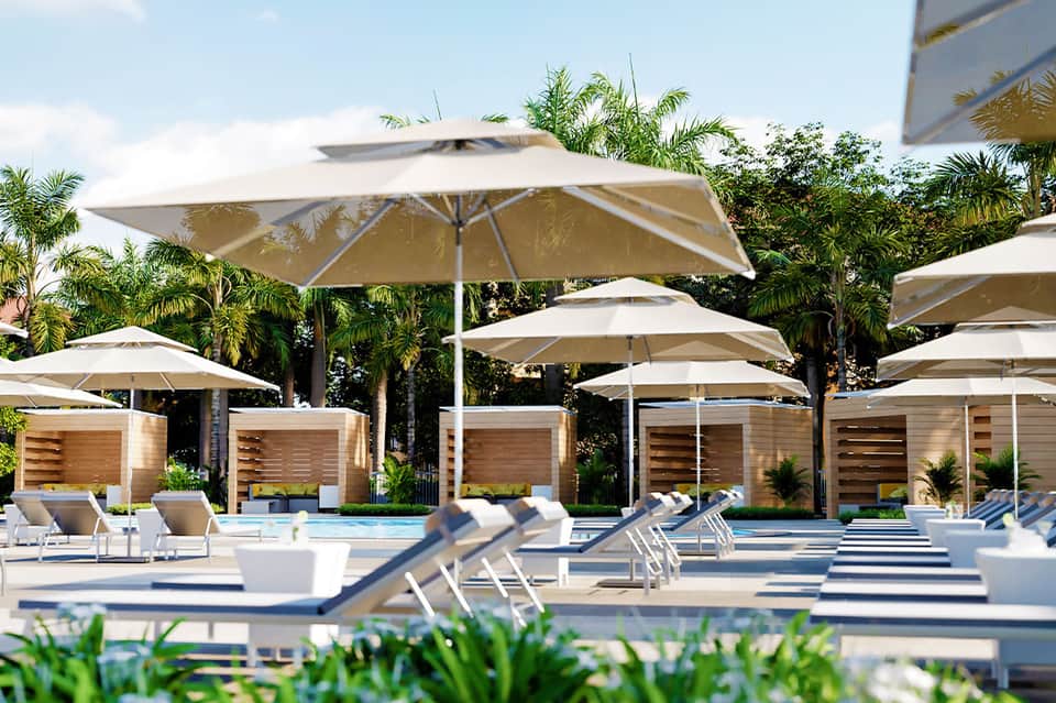 Luxury resort pool deck with white umbrellas, lounge chairs, and palm trees in daylight