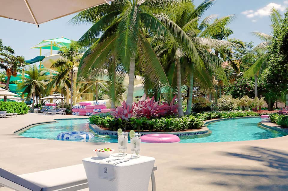 Tropical resort pool with palm trees, pink floats, and lounge chairs
