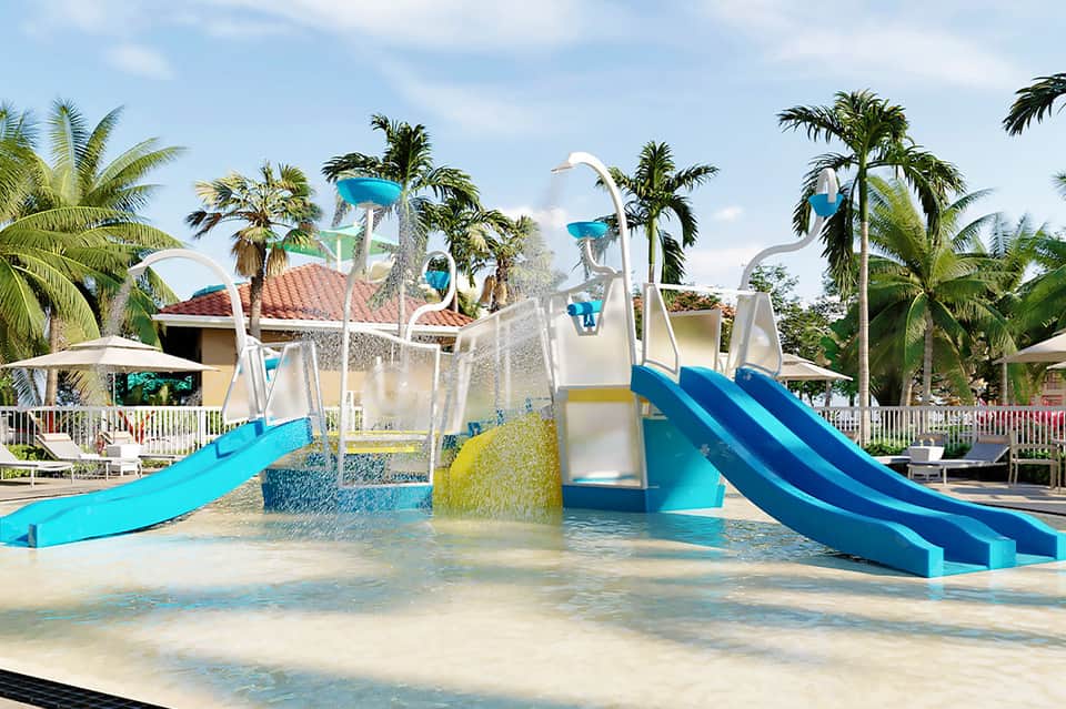 Water park with colorful slides, palm trees, and shallow splash area at tropical resort