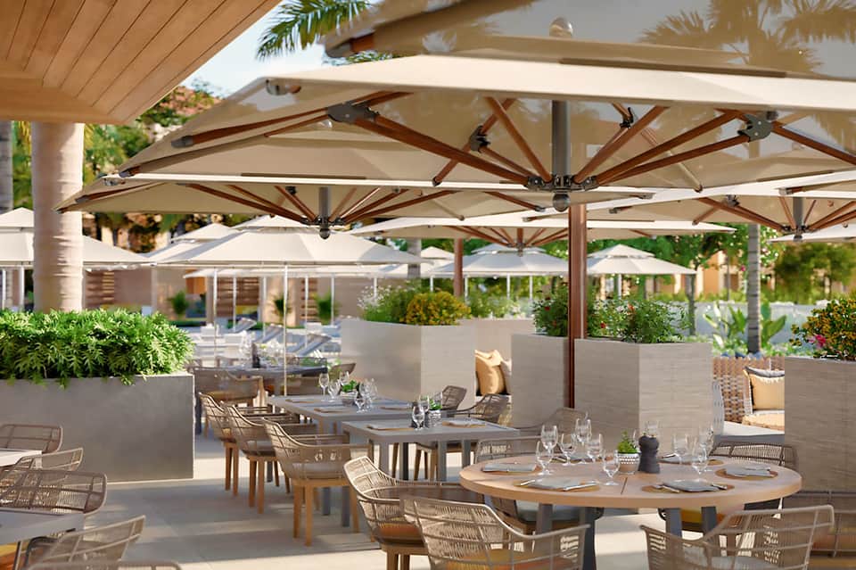 Upscale outdoor dining area with large umbrellas, wooden tables, and lounge seating