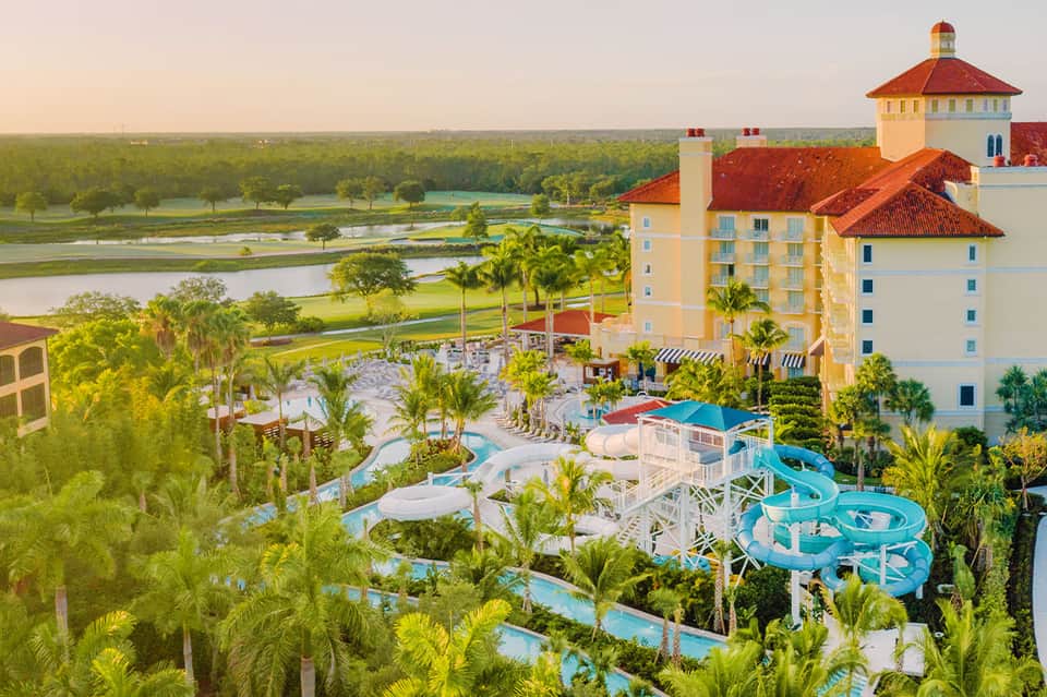 Aerial view of castle-style resort with water slides, pools, and manicured grounds