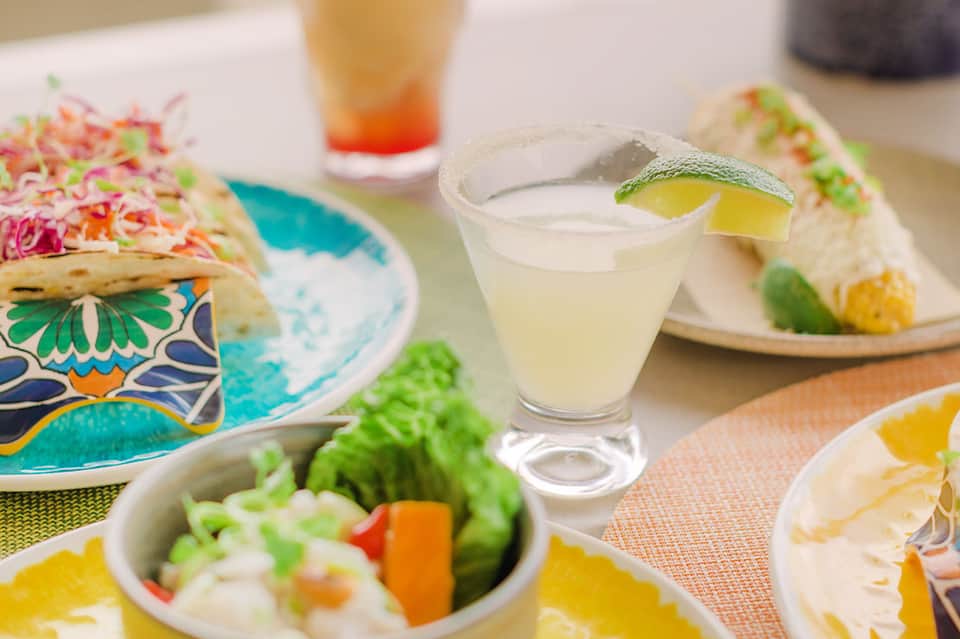 Colorful plated meals with lime cocktails on decorative dinnerware at outdoor dining setting
