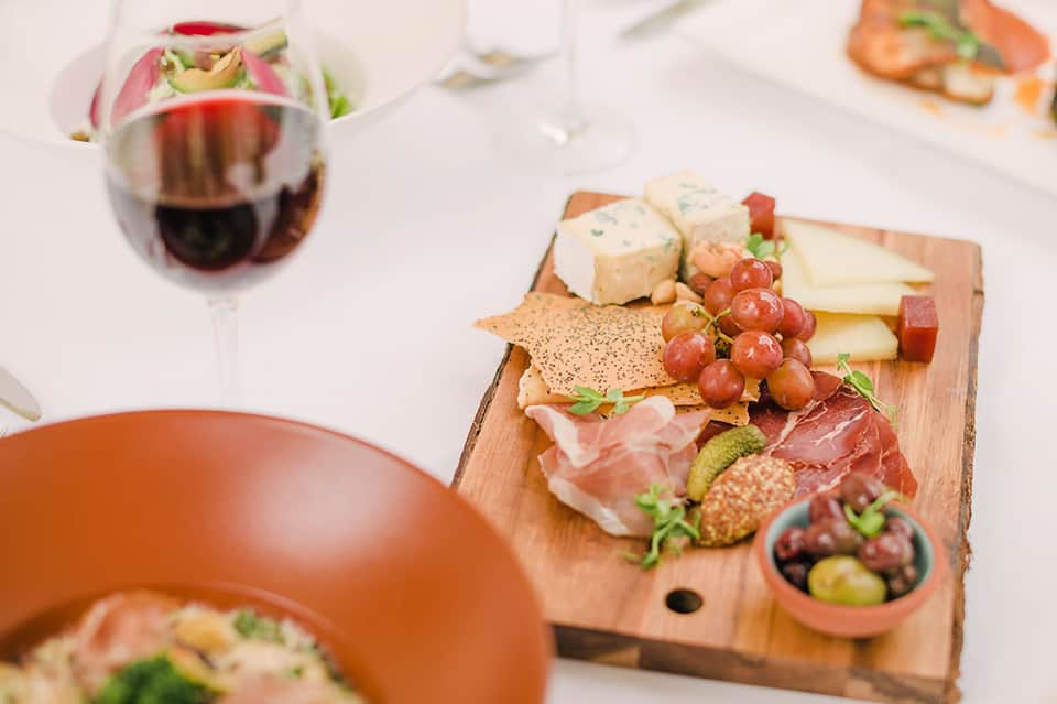 Charcuterie board with cured meats, cheeses, crackers, grapes, and wine glass