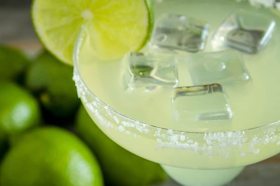 Margarita cocktail with lime wheel and salt rim, ice cubes visible in the glass