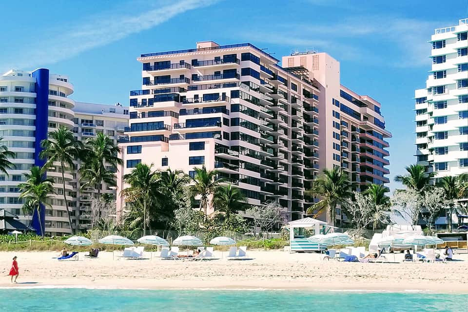 Beachfront resort with pink and white high-rise buildings, palm trees, and sandy beach