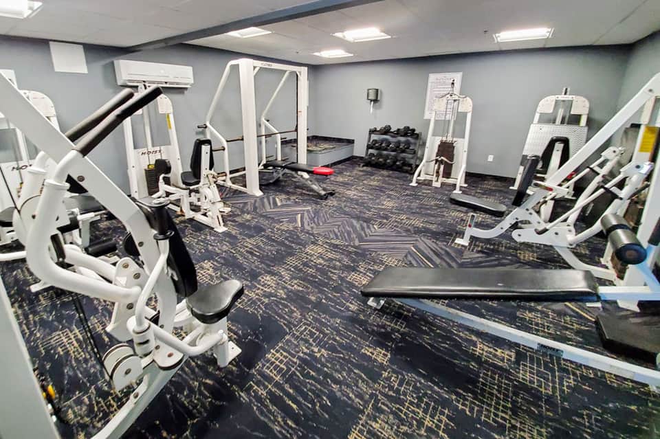 Modern fitness center with white exercise equipment and dark patterned flooring