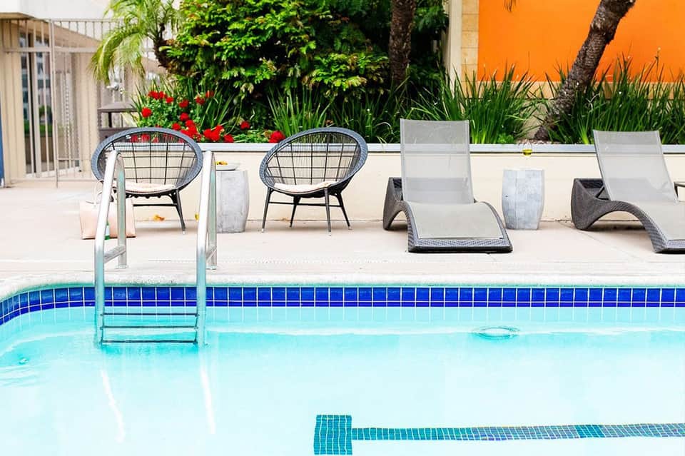 Poolside seating with modern lounge chairs and round accent tables by bright blue pool