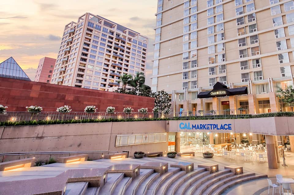 Contemporary hotel courtyard with CAL Marketplace entrance and sculptural water features at dusk