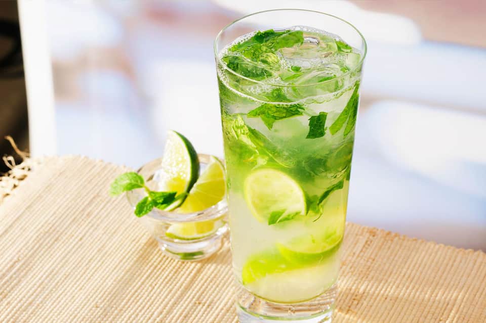 Fresh mojito cocktail with lime and mint on a textured outdoor surface