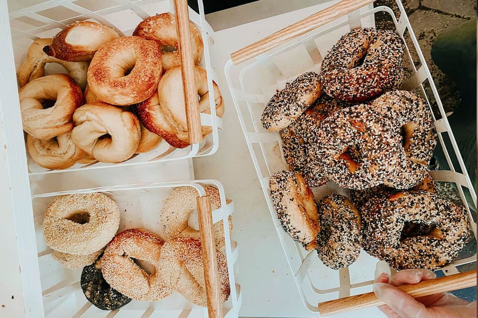 Assorted fresh bagels in white boxes, including cinnamon sugar and everything seed varieties