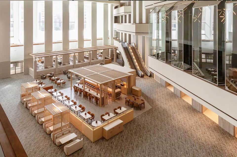 Modern hotel atrium with wooden furniture, escalators, and natural lighting from above