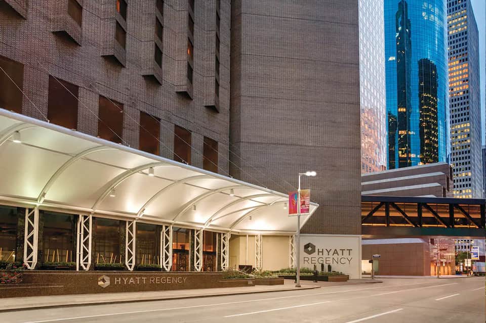 Hyatt Regency hotel entrance with illuminated canopy at dusk in urban downtown setting