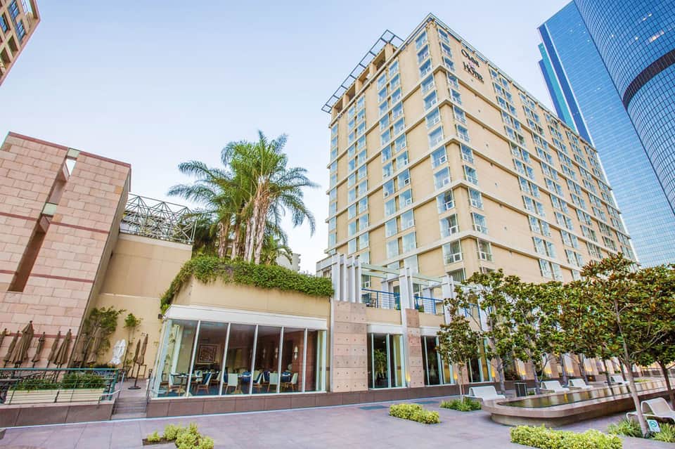 Beige residential tower with ground-level retail space and landscaping in urban setting