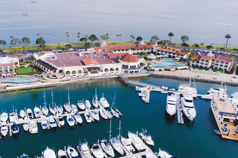 Aerial view of coastal resort with marina, boats, and Mediterranean architecture