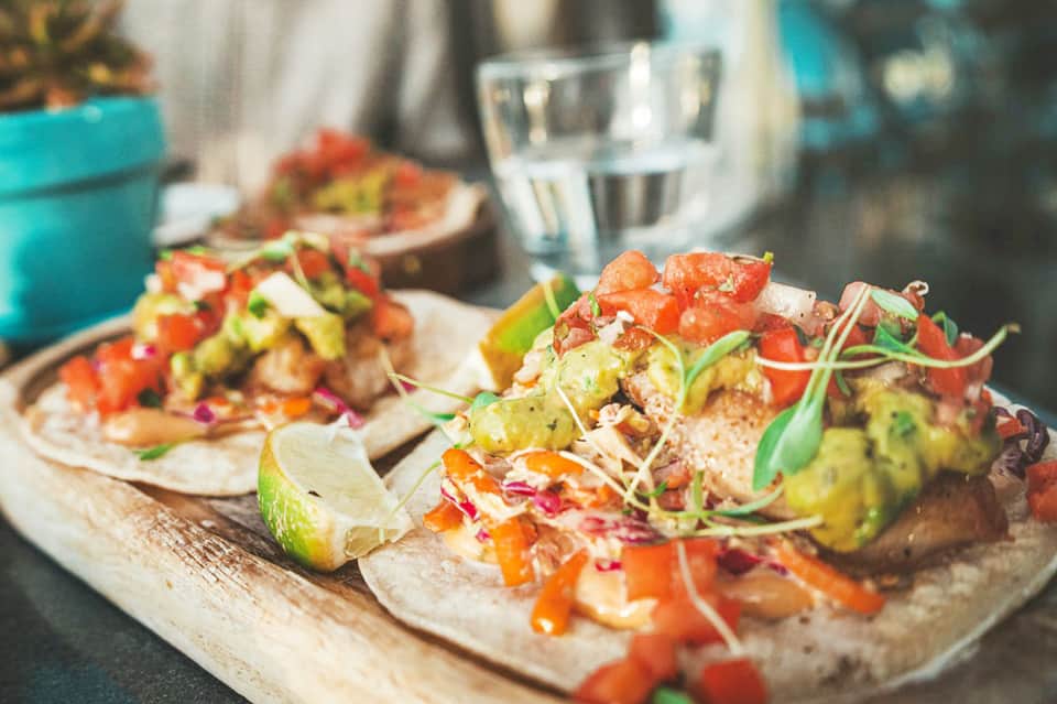 Gourmet tacos with fresh toppings and lime garnish served on wooden board