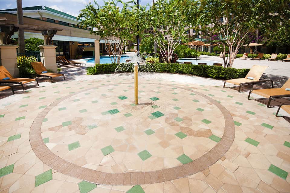 Elegant resort courtyard with geometric patterned pavement, fountain, and lounge chairs