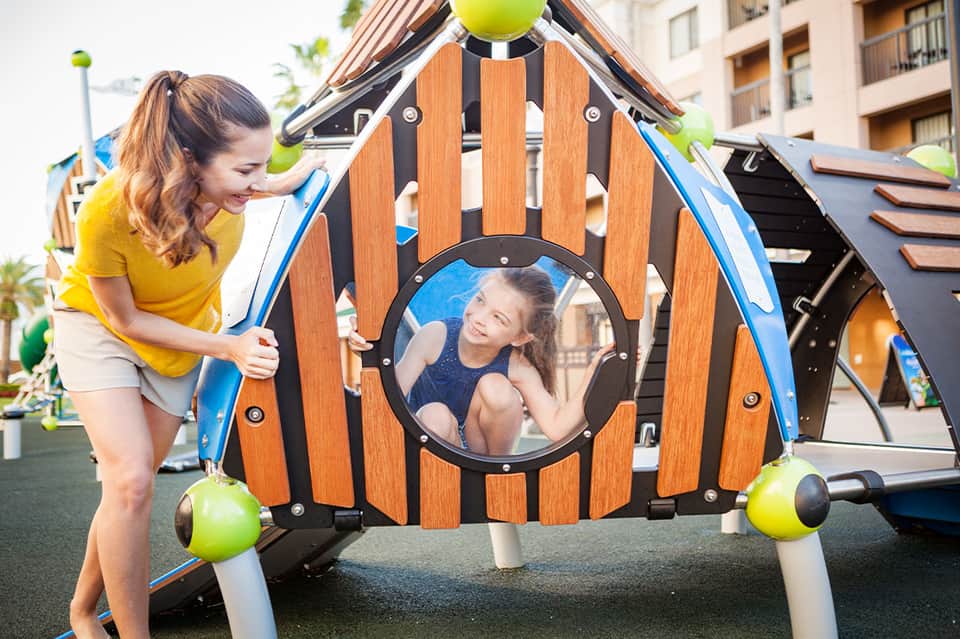 Child playing in wooden play structure shaped like a house at resort recreation area