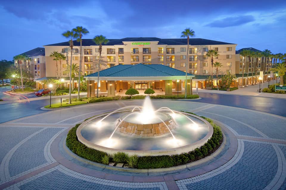Hotel exterior at dusk with illuminated fountain in courtyard