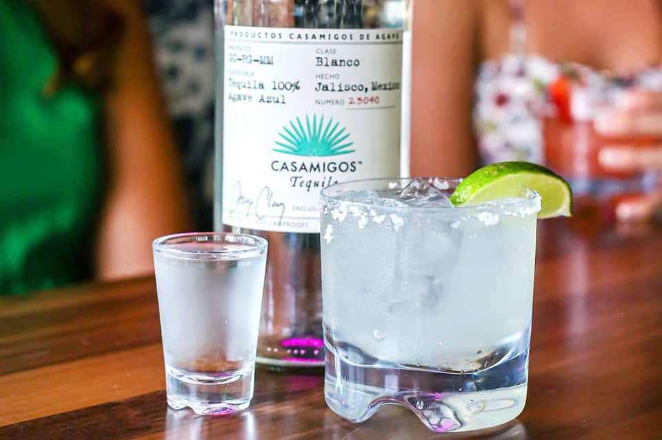 Casamigos tequila bottle with margarita cocktail and lime garnish
