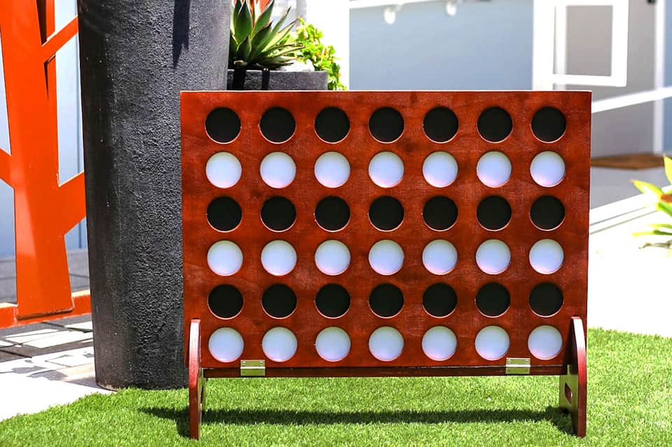 Giant red Connect Four game displayed on lawn at resort with building in background