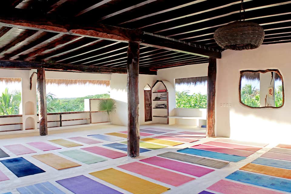 Colorful yoga studio with multicolored mats, wooden beams, and panoramic windows