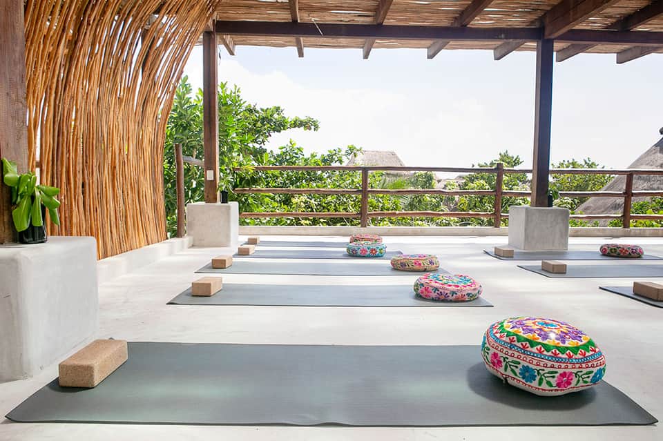 Yoga studio with wooden pergola, colorful meditation cushions, and mountain landscape views