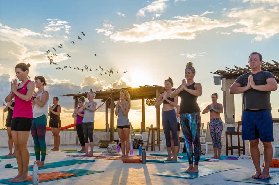 Beachfront group yoga and meditation class at sunset with participants on mats