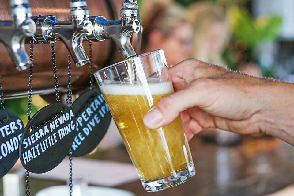 Bartender pouring craft beer from tap into a glass at an outdoor bar
