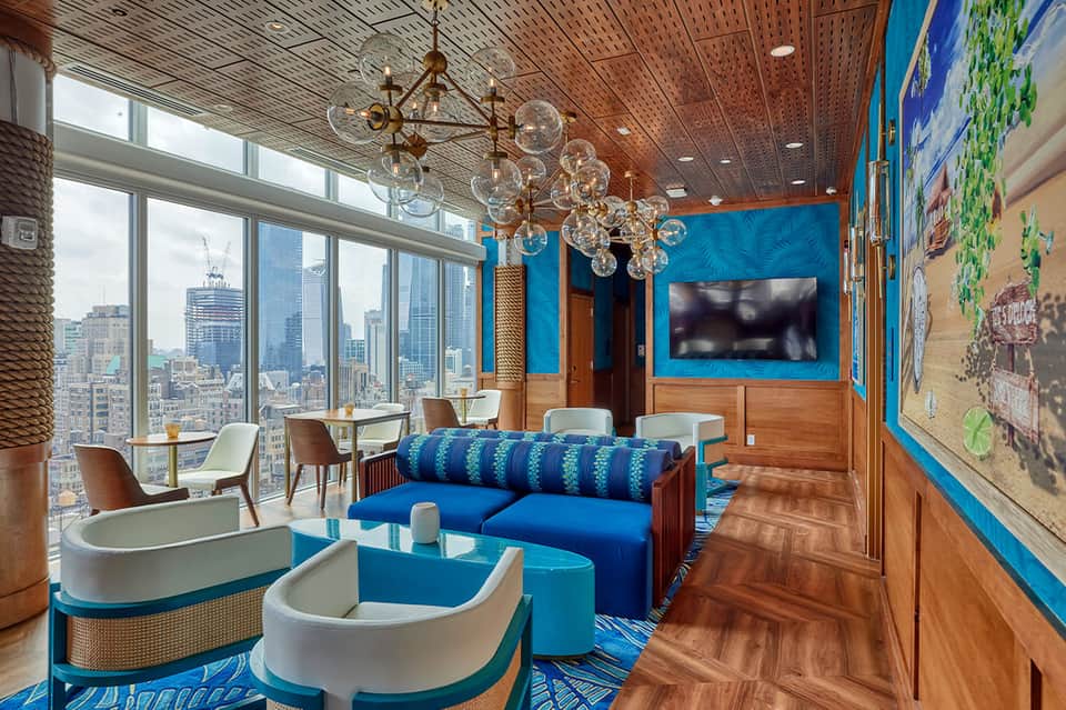 Modern hotel lounge with blue accents, bubble chandelier, skyline views through floor-to-ceiling windows