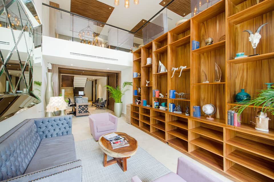 Contemporary hotel lobby with wood shelving, tufted sofa, and two-story open floor plan design