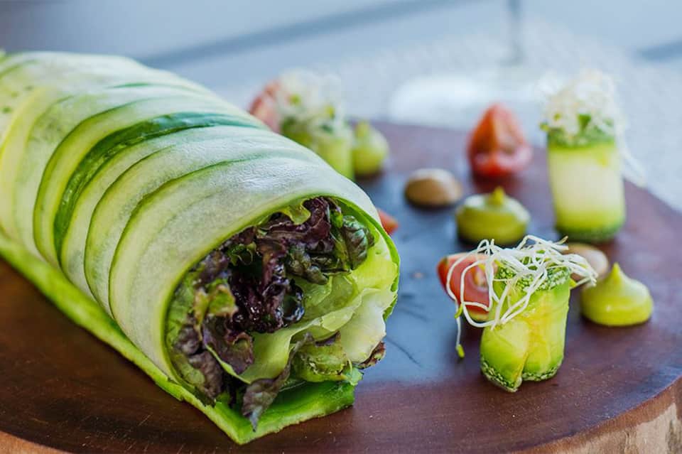 Gourmet green vegetable wraps and appetizers with fresh microgreens on dark serving board