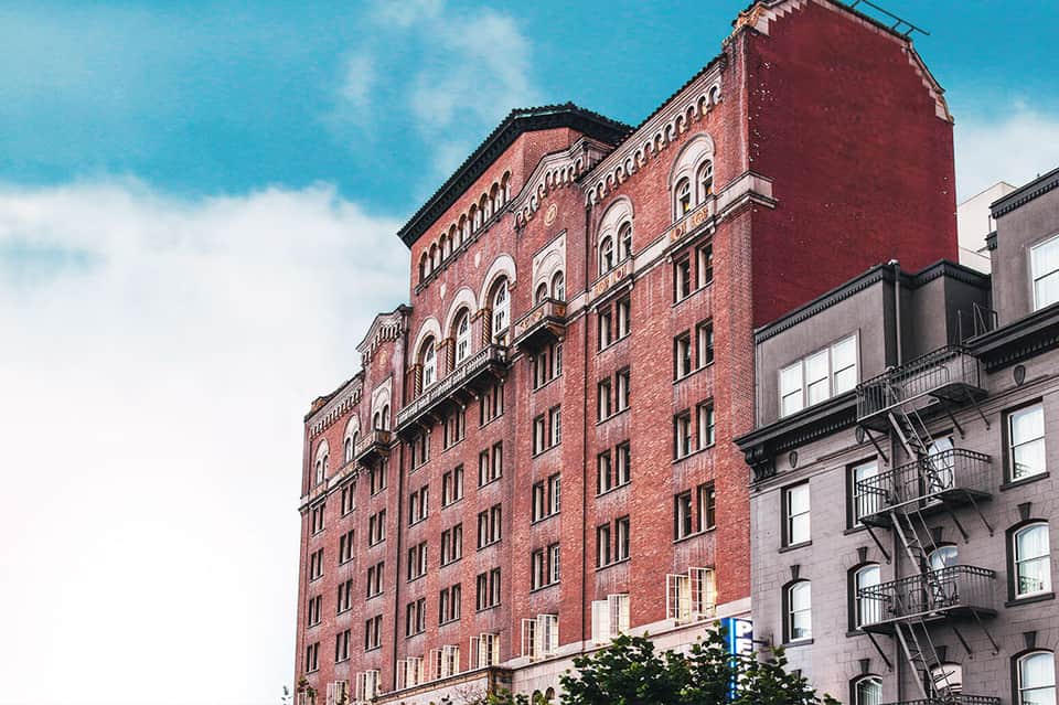 Historic red brick building with arched windows and fire escapes in urban setting