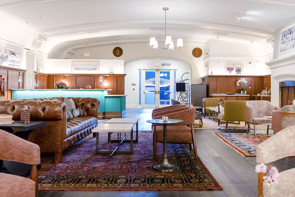 Upscale hotel lobby with leather seating, wooden reception desk, decorative rugs, and arched ceiling