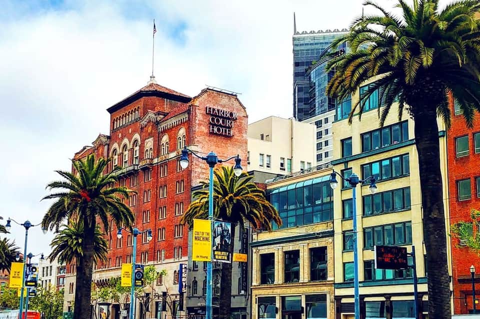 Historic Harbor Court Hotel building with red brick architecture surrounded by palm trees and modern buildings