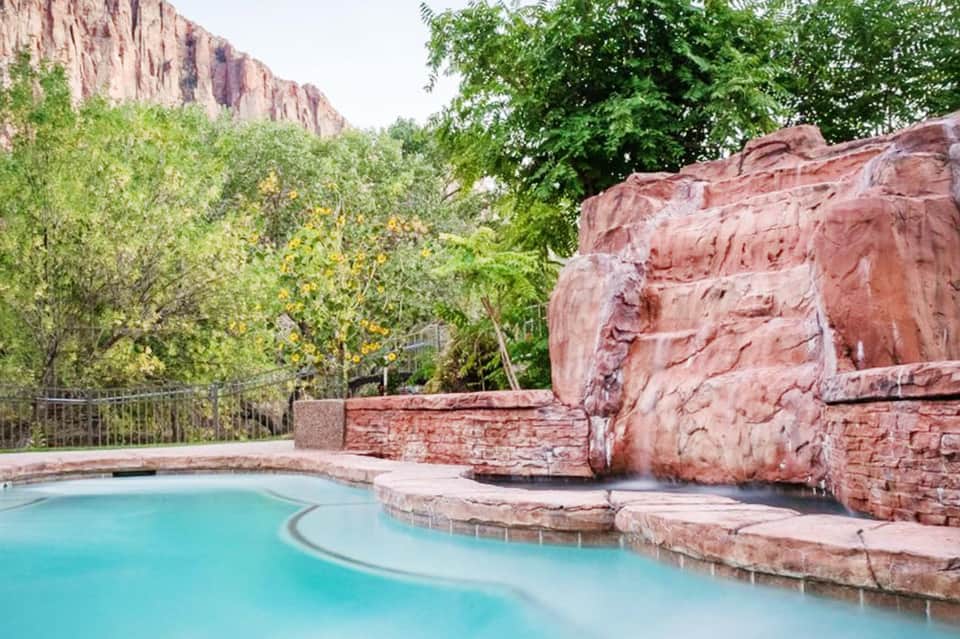 Turquoise pool nestled among red rock formations and desert vegetation