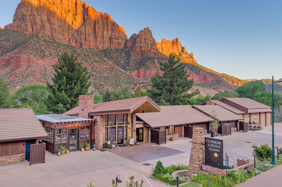 Clifftop lodge with red rock formations in background, stone architecture nestled in desert landscape