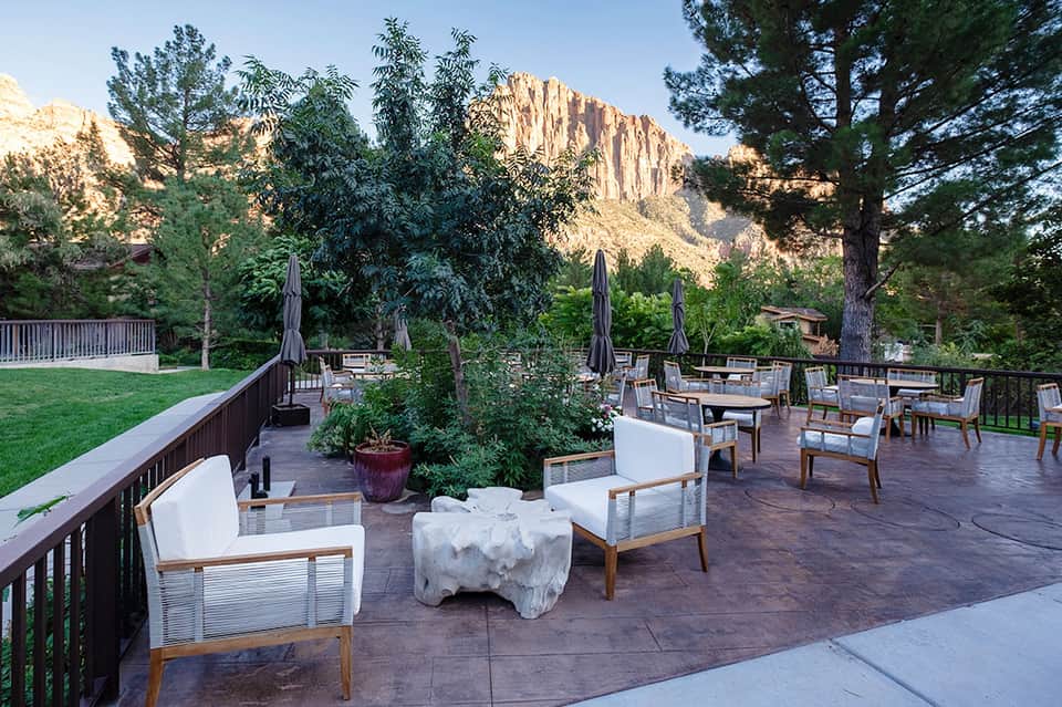 Outdoor patio with modern seating, fire pit, and mountain backdrop at dusk