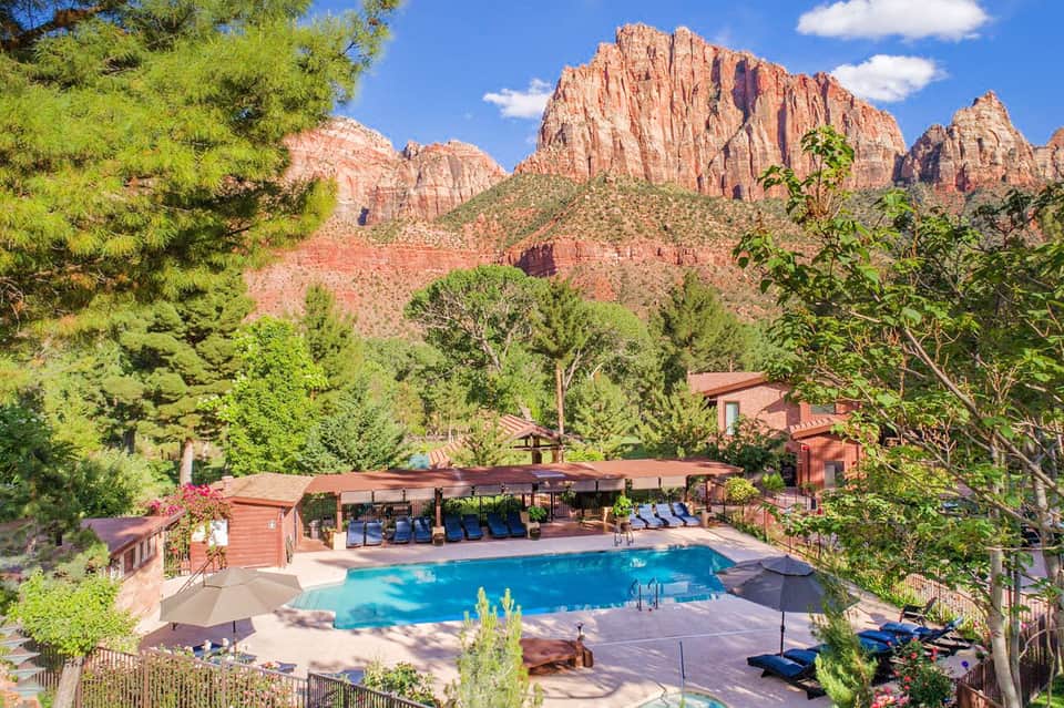 Resort pool with red rock mountain backdrop, surrounded by lounge chairs and desert landscaping
