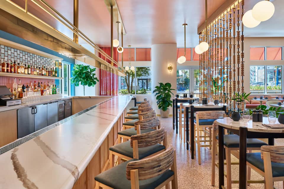 Contemporary bar and lounge with wooden chairs, pendant lighting, and colorful accent walls