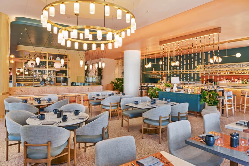Modern restaurant dining room with curved booths, pendant lighting, and bar area