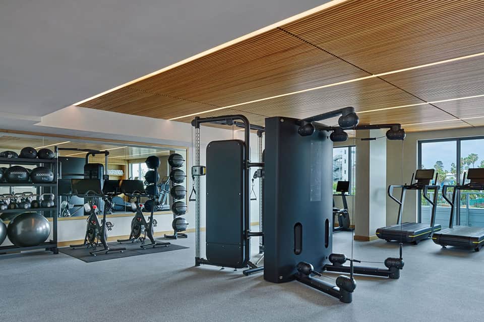 Modern fitness center with exercise equipment, weights, treadmills, and floor-to-ceiling windows