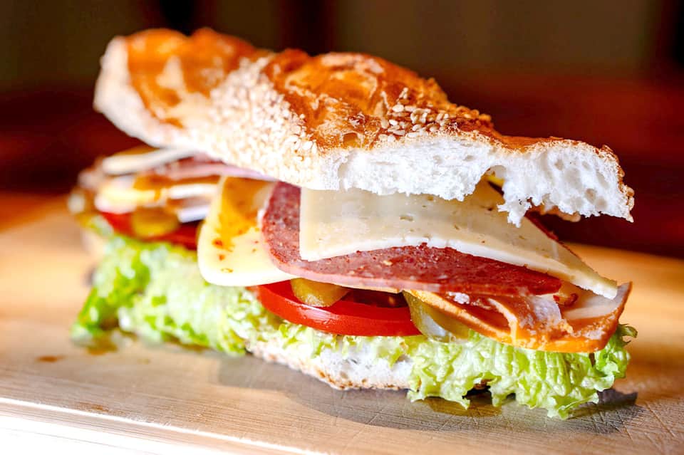 Gourmet sandwich with fresh lettuce, tomato, deli meats, and cheese on crusty bread