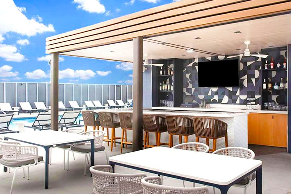 Modern rooftop bar and lounge area with ocean views, white umbrellas, and contemporary furniture