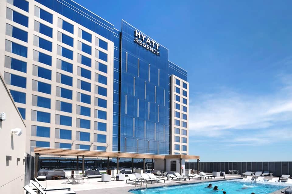Hyatt Regency hotel exterior with rooftop pool and lounge area under blue sky